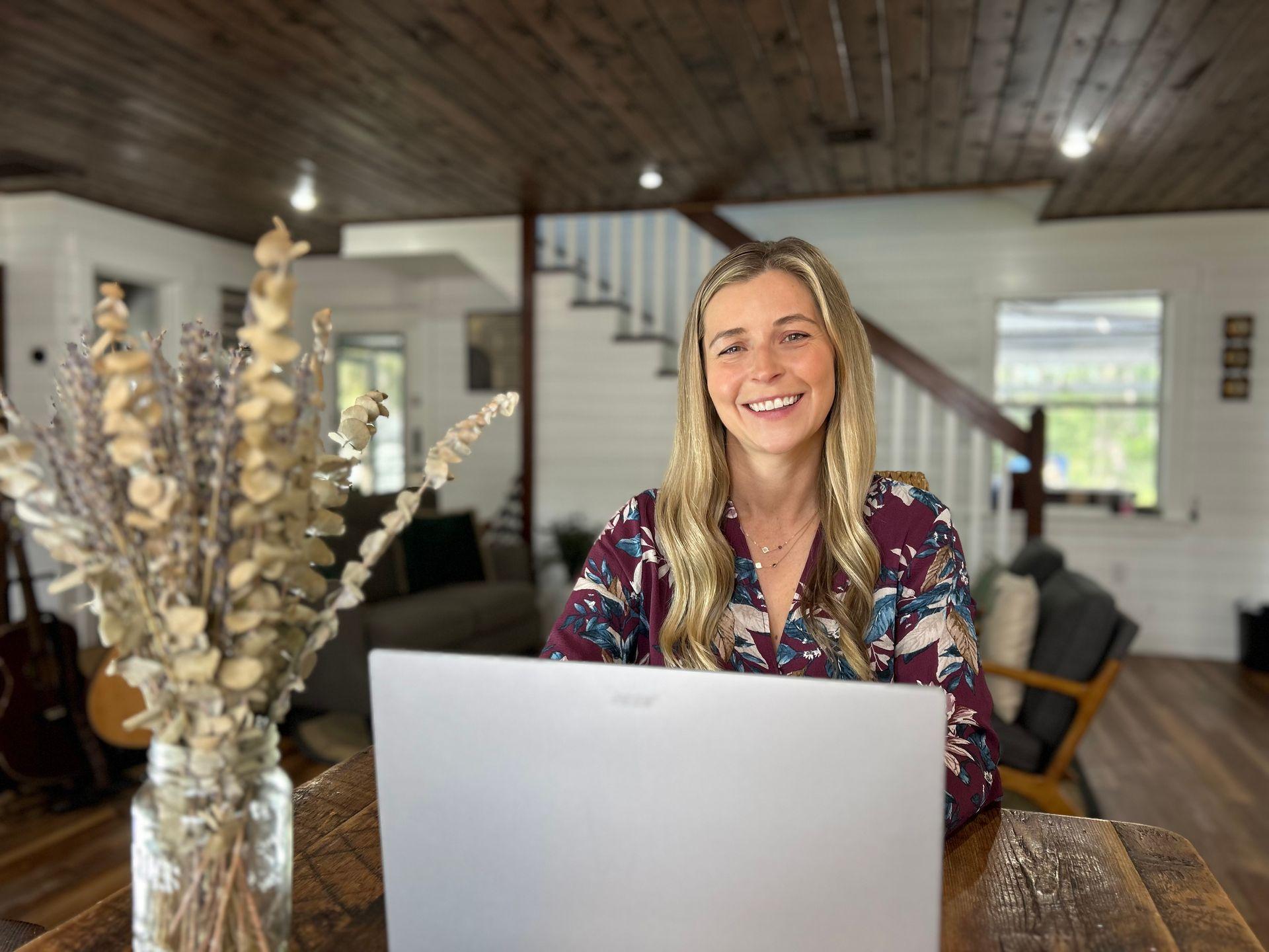 female nurse writer smiling behind laptop