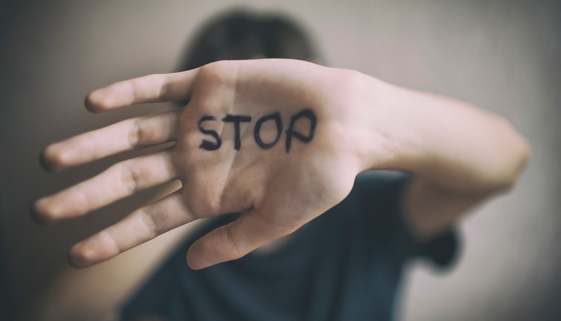 A 18-year-old guy protects himself with his hand with the inscription Stop