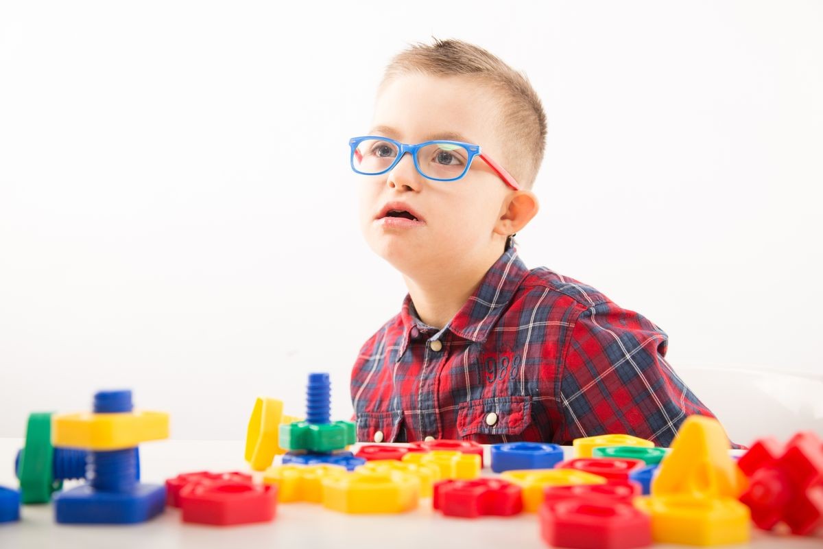 Motor therapy. Boy with down syndrome playing with toy and doing threading activities for hand therapy. 