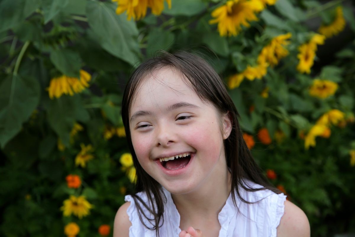 Portrait of little girl with Down Syndrome smiling in the garden