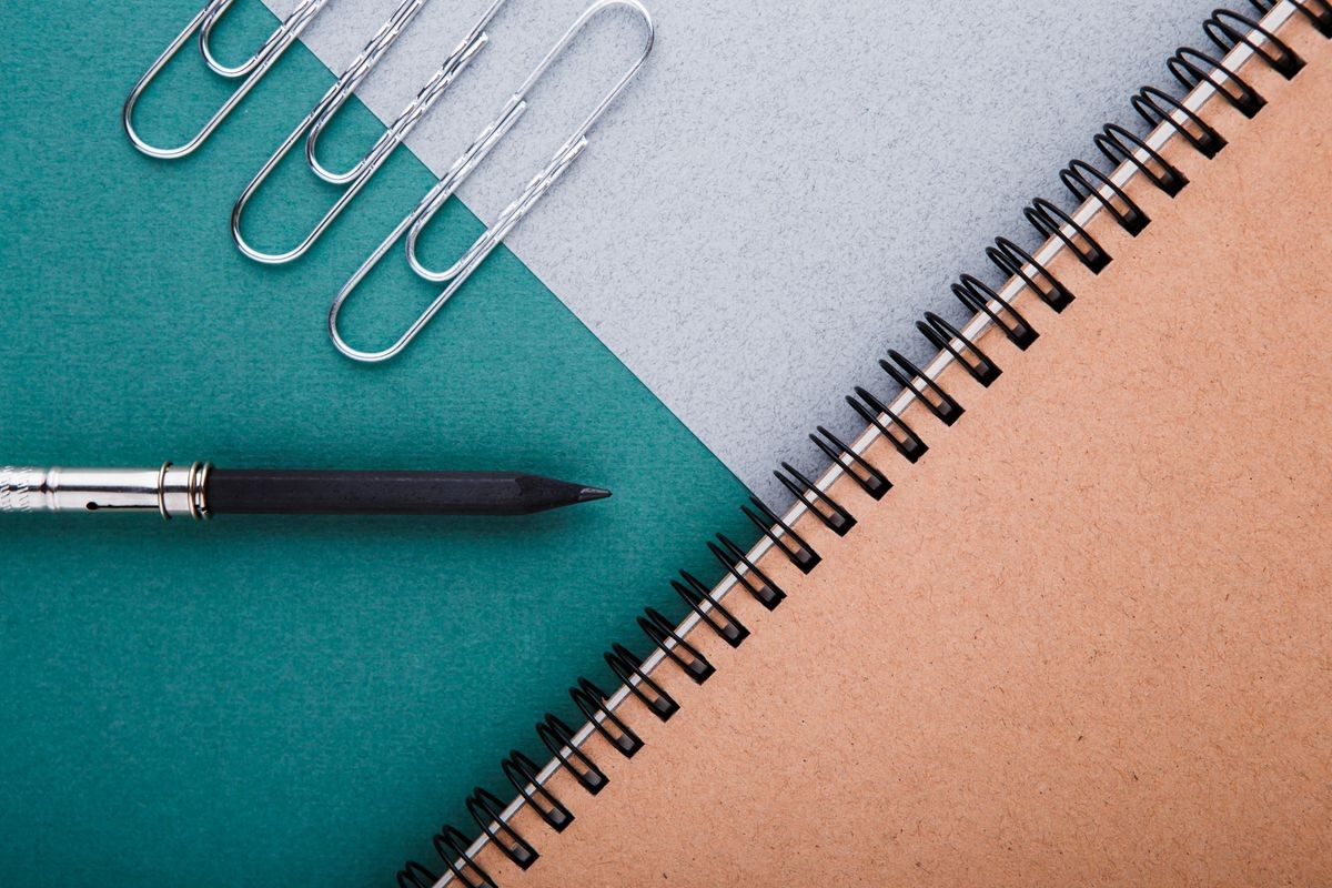 A pencil, a pencil sharpener and crafting notebooks on a green-gray background.